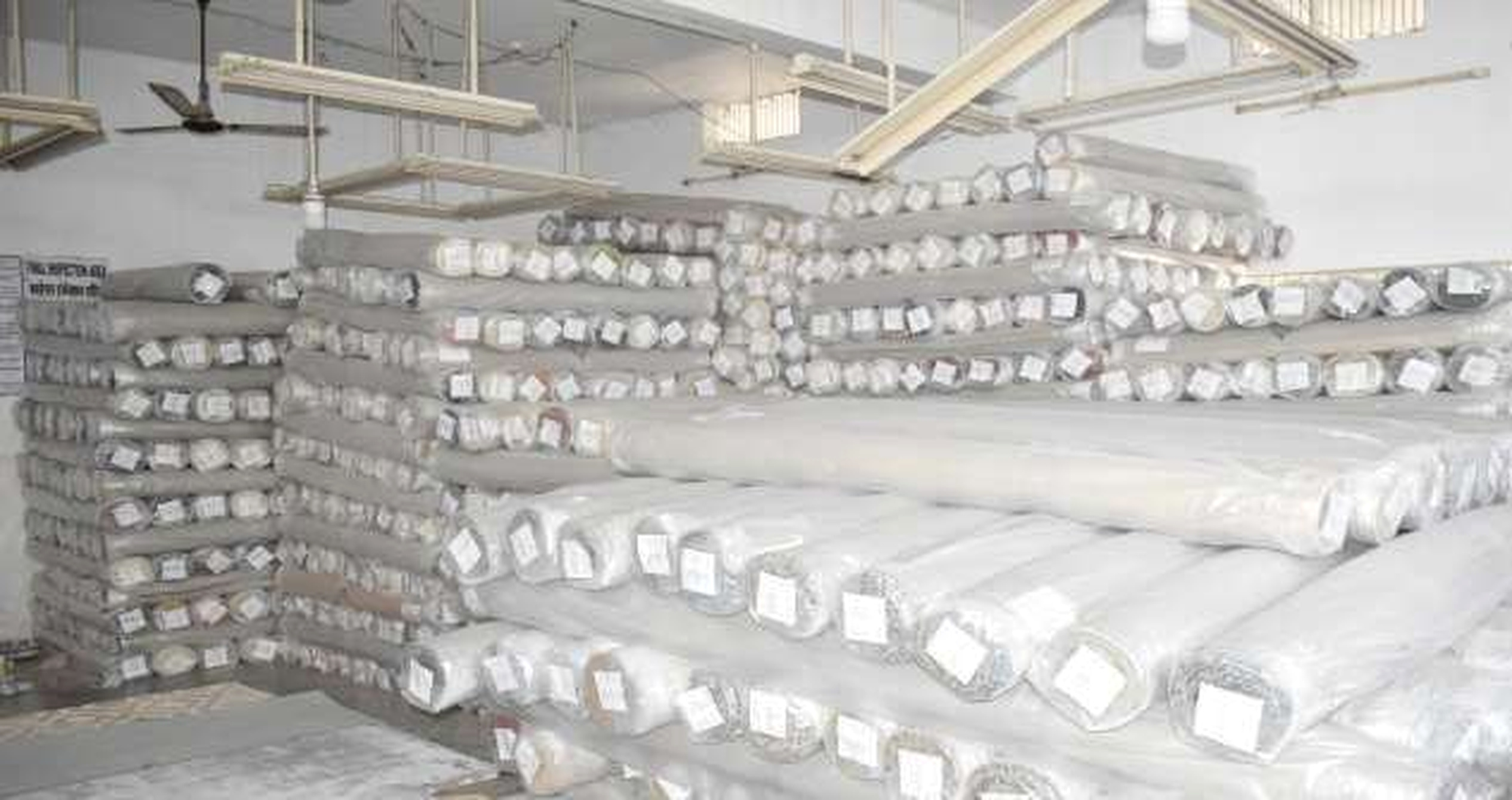 Finished textile rolls labeled and stacked in the warehouse
